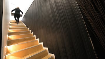 Eine Treppe mit Holzboden, die nach oben führt, gesäumt von dunkel strukturierten Wänden.