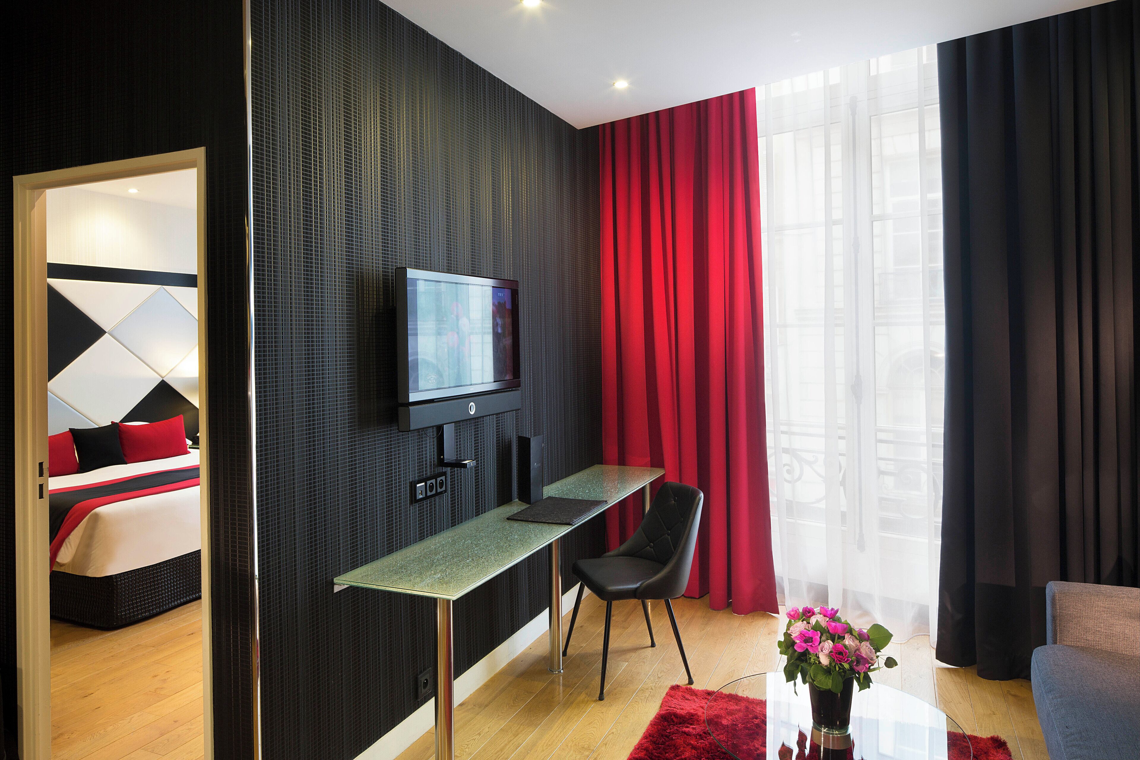 A modern hotel room with a bed, a TV, a desk, and a chair.