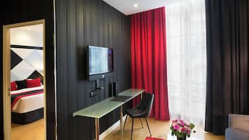 A modern hotel room with a bed, a TV, a desk, and a chair.