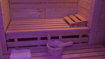 A wooden sauna bench with a wooden bucket and a towel.