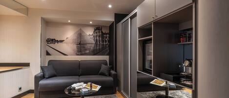 A modern living room with a sofa, a coffee table, and a large mirror reflecting the room.