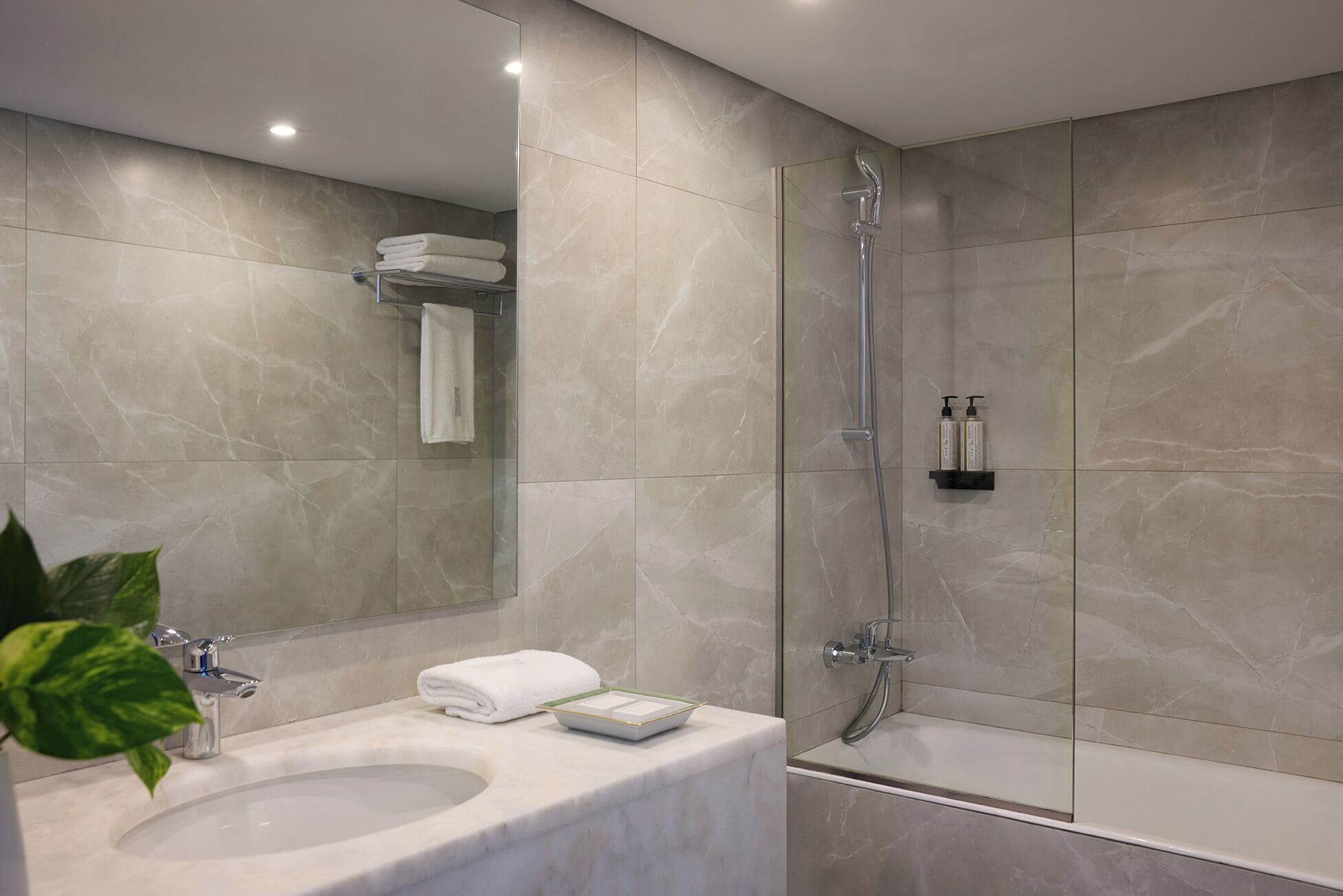 A modern bathroom with a marble sink, a glass-enclosed shower, and a large mirror.