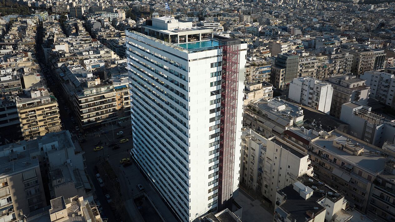 Un edificio de gran altura con varios pisos, rodeado de un entorno urbano denso.