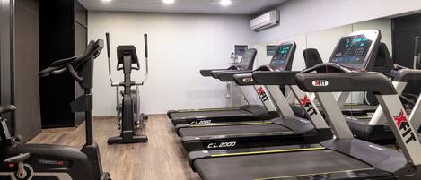 A gym with treadmills, a stationary bike, and a rowing machine.