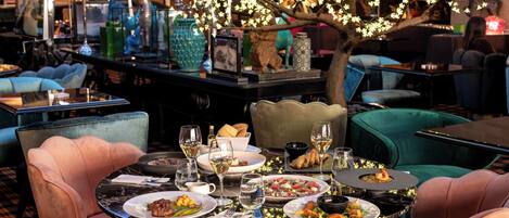 A restaurant with round tables, chairs, and a decorative tree with lights.