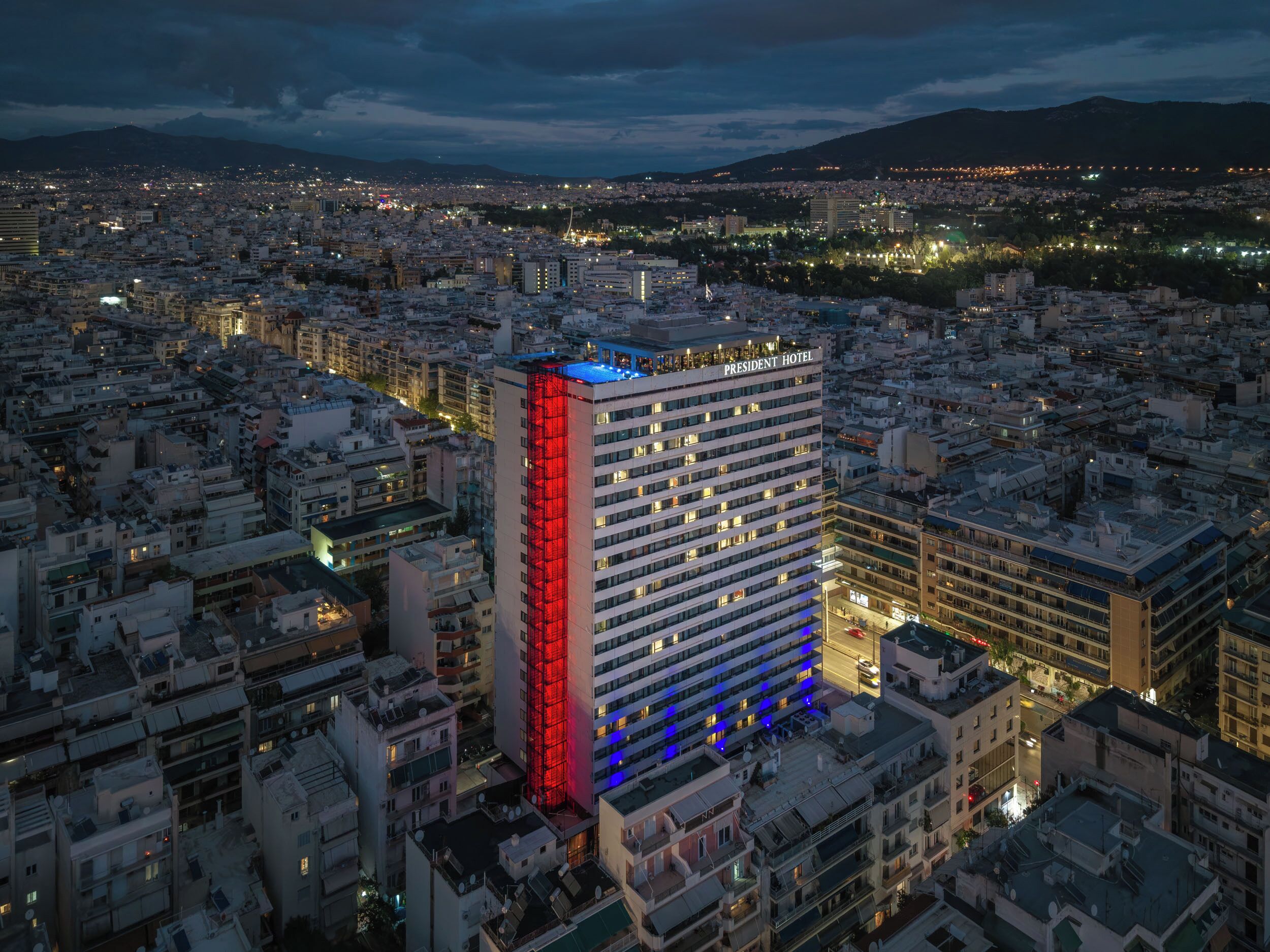 Un hotel moderno de gran altura, con varios pisos, rodeado de una zona urbana muy poblada.