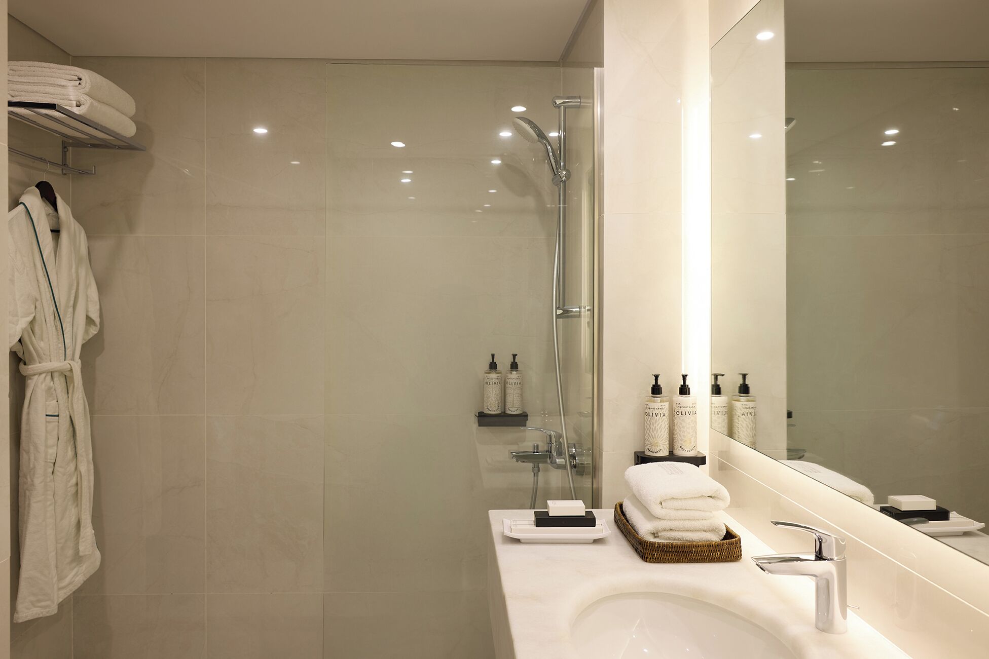 A modern bathroom with a glass-enclosed shower, a large mirror, and neatly arranged toiletries.