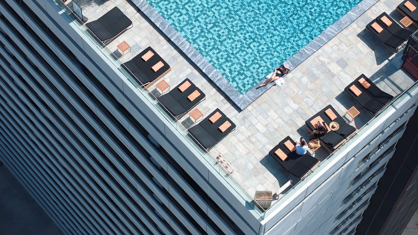 Un área de piscina en la azotea con sillones de descanso y un pequeño espacio para sentarse.
