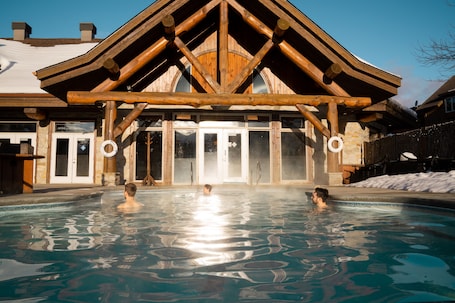 Una piscina techada, una piscina al aire libre, sombrillas