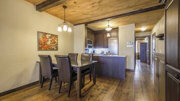 A dining area with a wooden table and chairs, a kitchen with modern appliances, and a wooden ceiling.