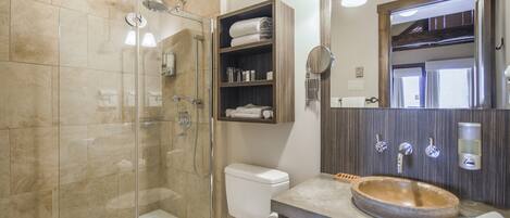 A modern bathroom with a glass-enclosed shower, a toilet, a sink with a wooden basin, and a mirror with a wooden frame.