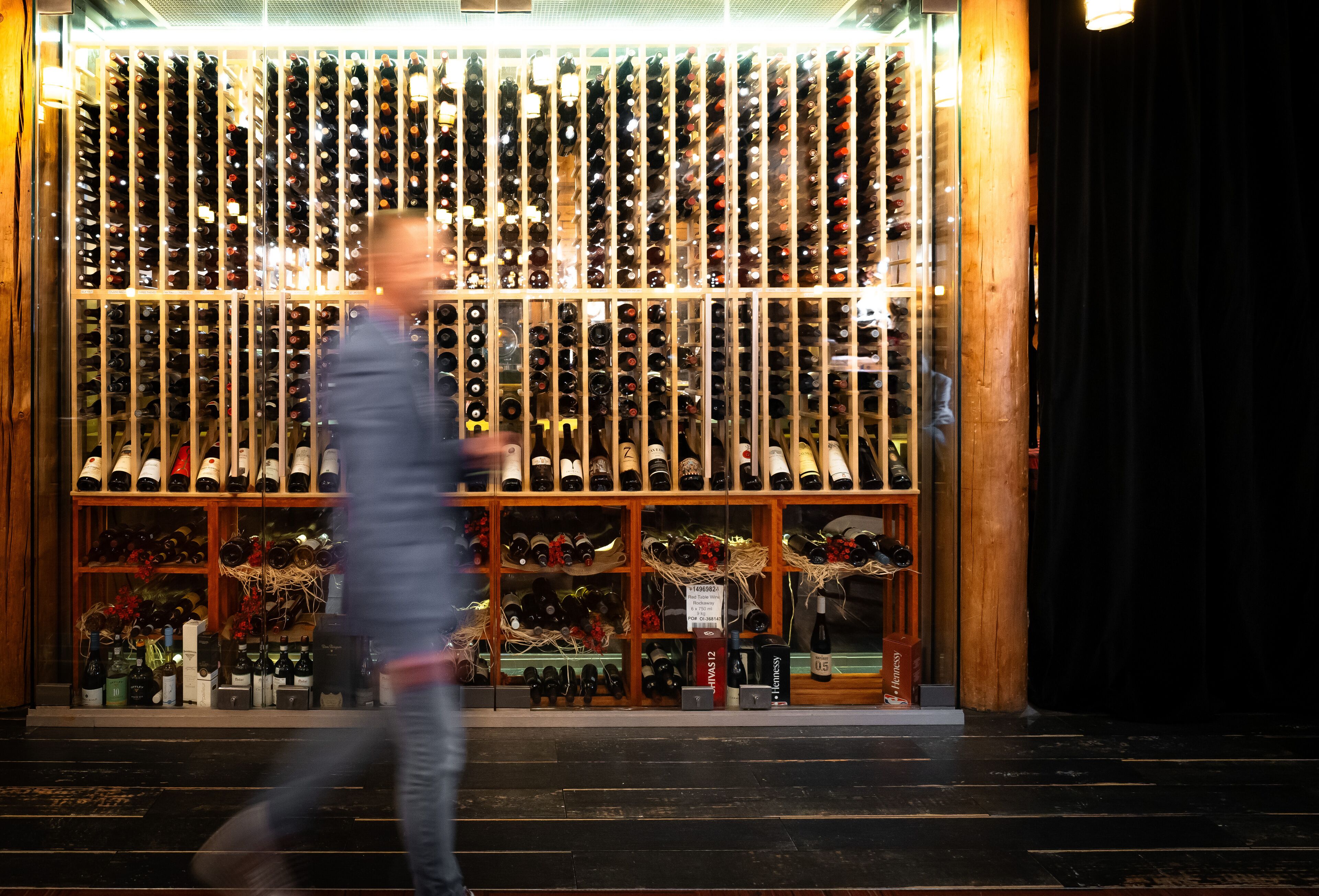 Una bodega con hileras de botellas de vino, estantes de madera y algunos objetos decorativos.