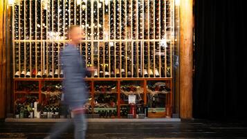 Una bodega con hileras de botellas de vino, estantes de madera y algunos objetos decorativos.