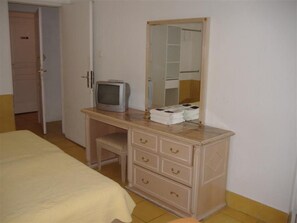 A bedroom with a bed, a dresser with drawers, a television, and a mirror. - Hotel Europa (Montpellier)