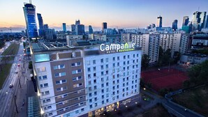 Un hotel con varios pisos, una terraza en la azotea y vistas del horizonte urbano.