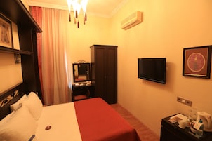 Habitación de hotel con cama, escritorio, armario, televisor y minibar.