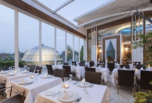 A restaurant with tables set for dining, large windows, and a view of a dome structure.