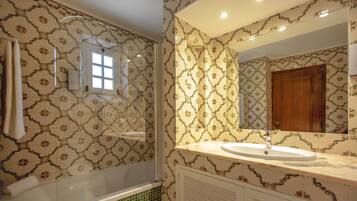 A bathroom with patterned tiles, a bathtub, a sink, and a mirror.