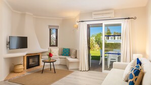 Una sala de estar moderna con chimenea, un televisor de pantalla plana, un sofá y vistas del jardín a través de un ventanal corredero.
