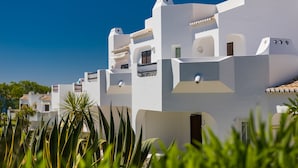 Un edificio blanco con varios balcones y un cielo azul despejado.