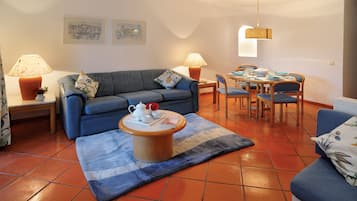 A living room with a sofa, coffee table, and dining table set with chairs.