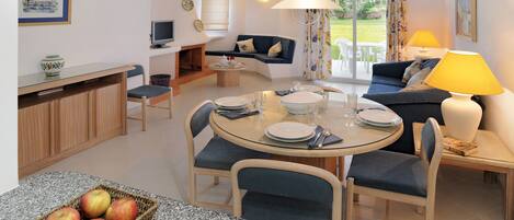 A modern living room with a dining area, a sofa, a TV, and a lamp.