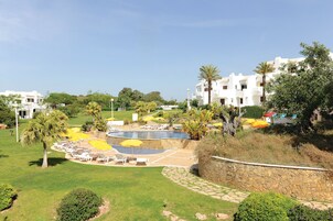Un resort con piscina, sillas de descanso y palmeras.