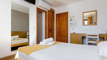 Una habitación de hotel con cama, escritorio, espejo y armario.