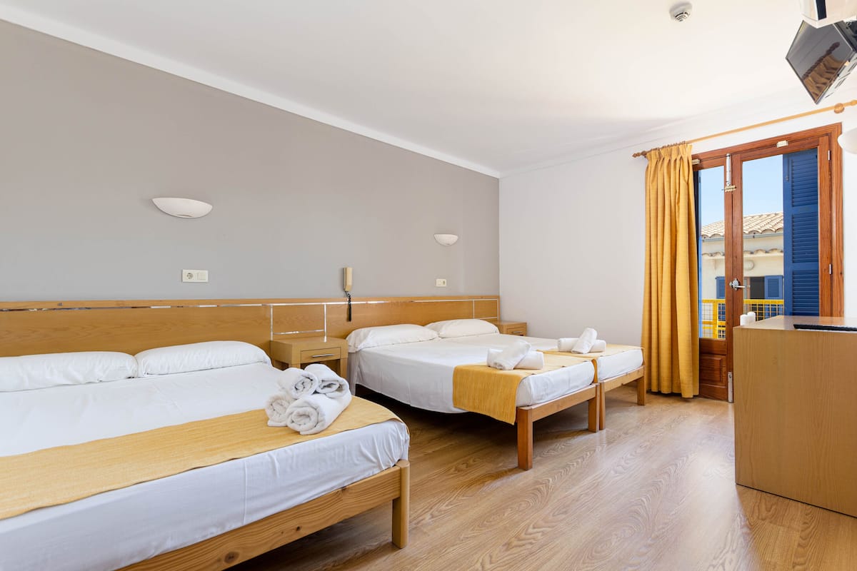 A hotel room with two beds, wooden headboards, white linens, and a wooden desk.
