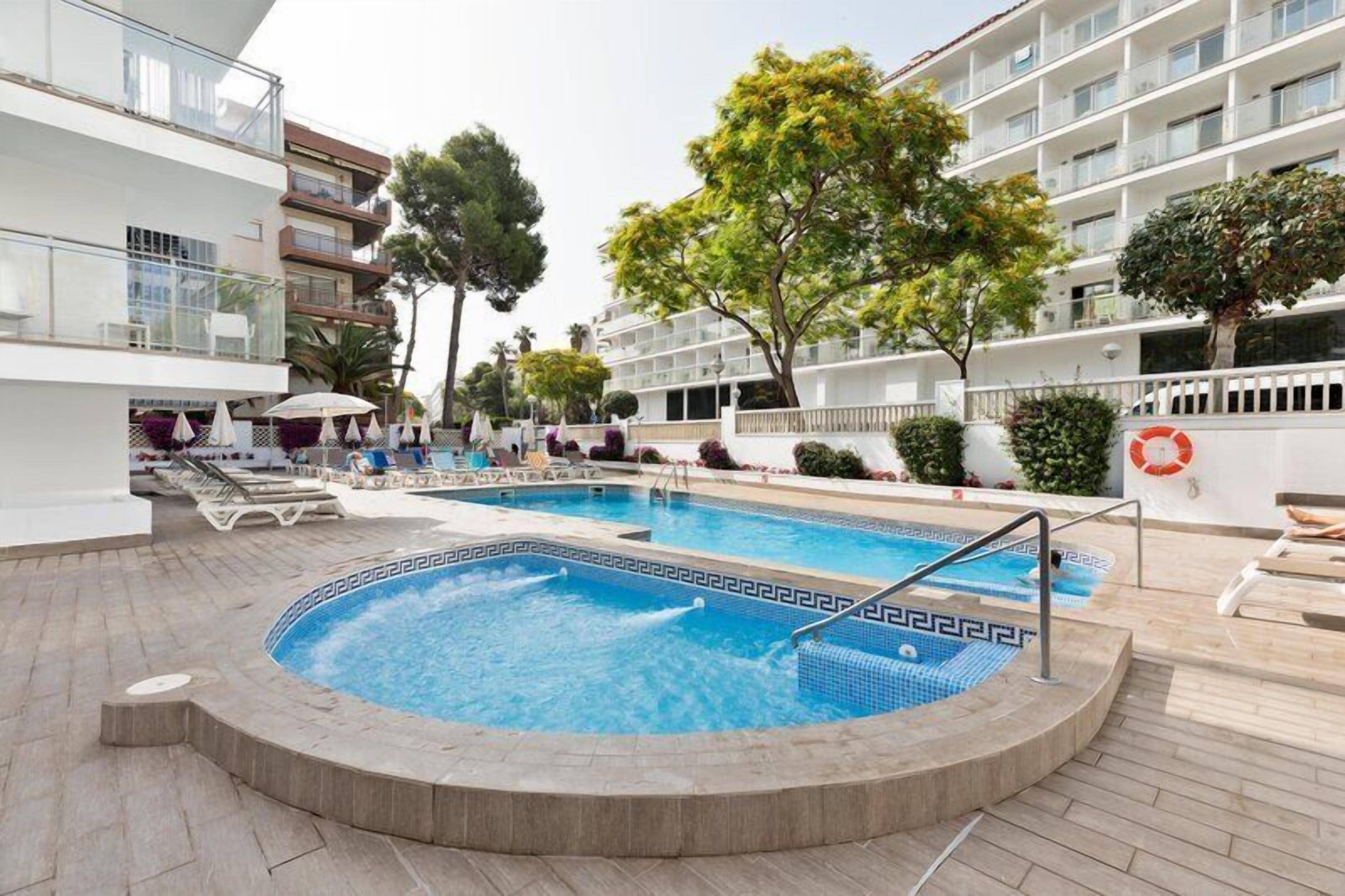 Una piscina al aire libre, sombrillas, sillones reclinables de piscina