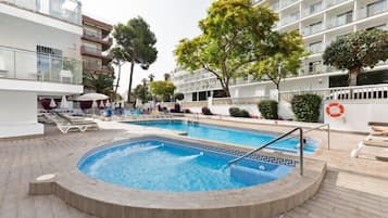 Una piscina al aire libre, sombrillas, sillones reclinables de piscina