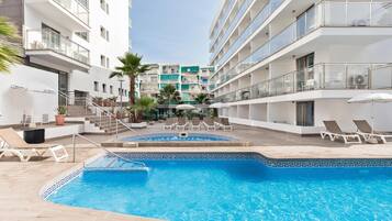 Een buitenzwembad, parasols bij het zwembad en ligstoelen