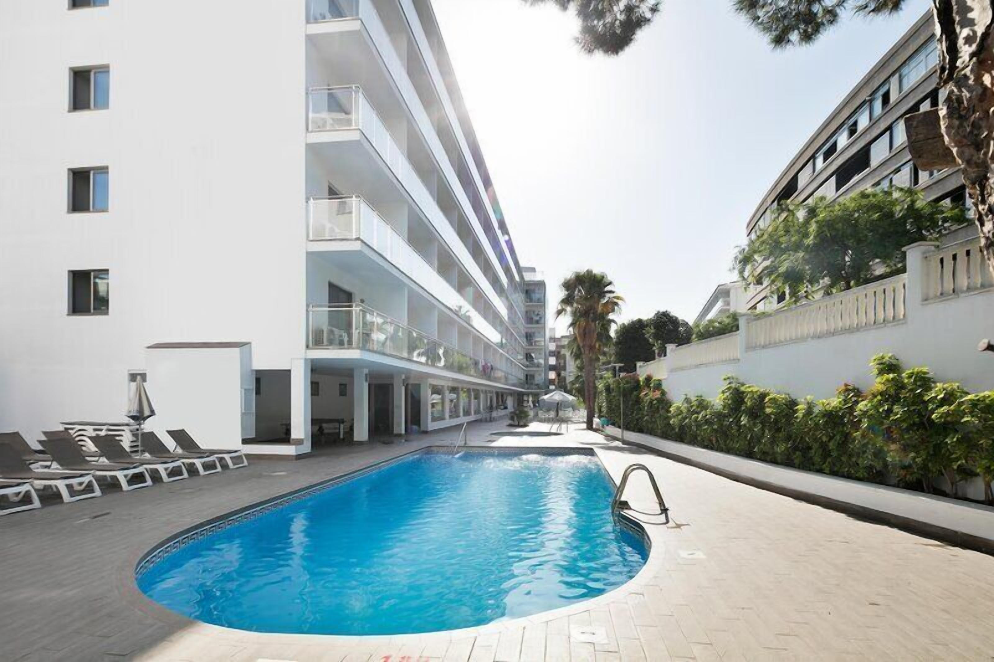 Una piscina al aire libre, sombrillas, tumbonas