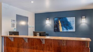 A reception desk with two computers, a framed sign, and a large abstract painting on the wall. - Econo Lodge (Montreal)