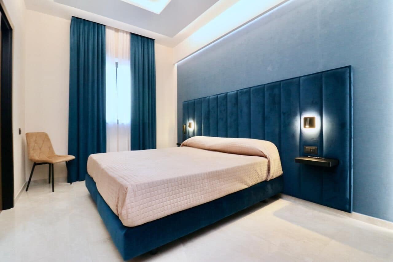 A modern bedroom with a large bed, a chair, and a blue accent wall.
