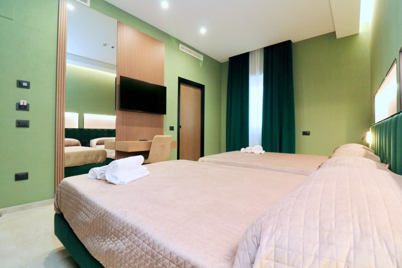 A hotel room with two beds, a TV, a mirror, and a wooden panel wall.