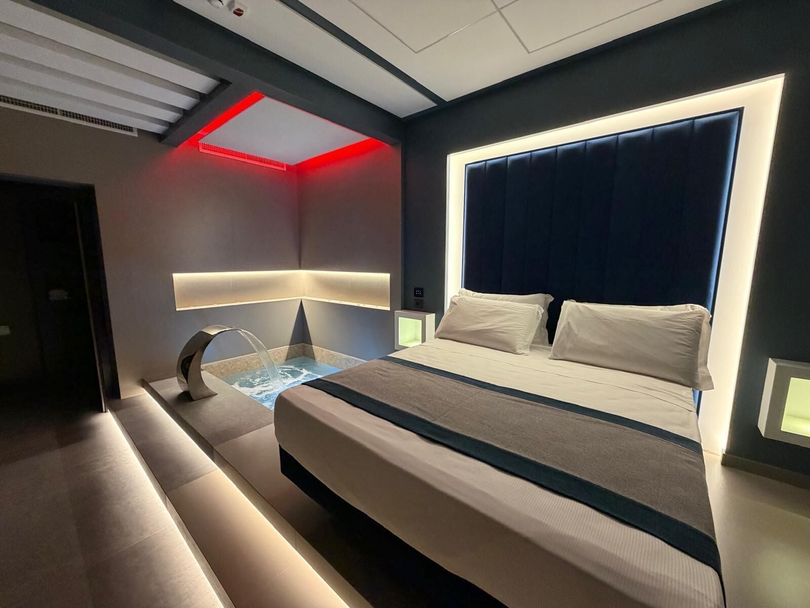 Ein modernes Hotelzimmer mit einem Bett, einer integrierten Wassereinrichtung und einem außergewöhnlichen Deckenstil.