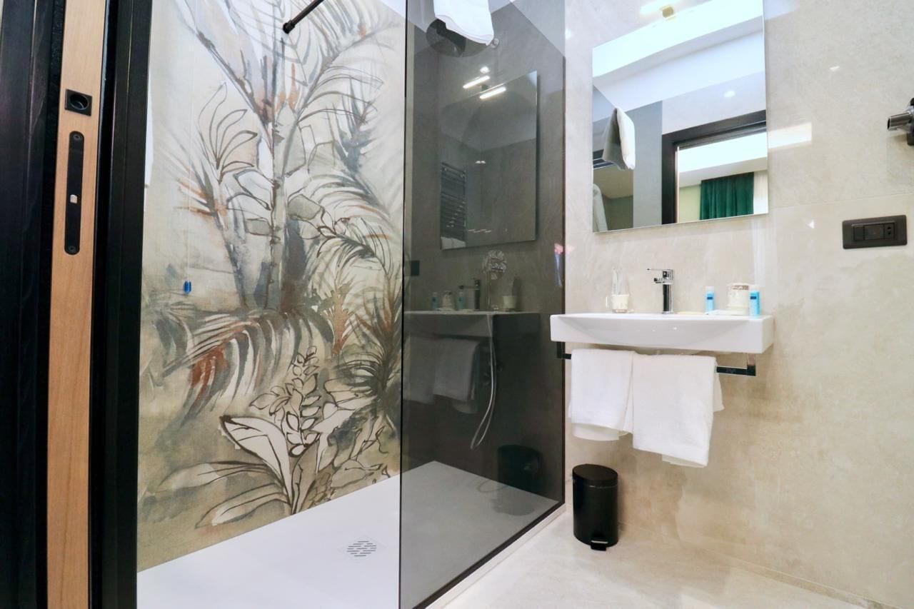 Un baño moderno con cabina de ducha de vidrio, un lavamanos blanco y un espejo sobre él.