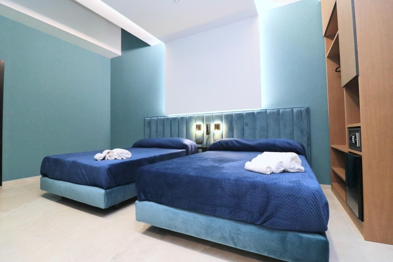 A hotel room with two beds, a flat-screen TV, and a wooden cabinet.