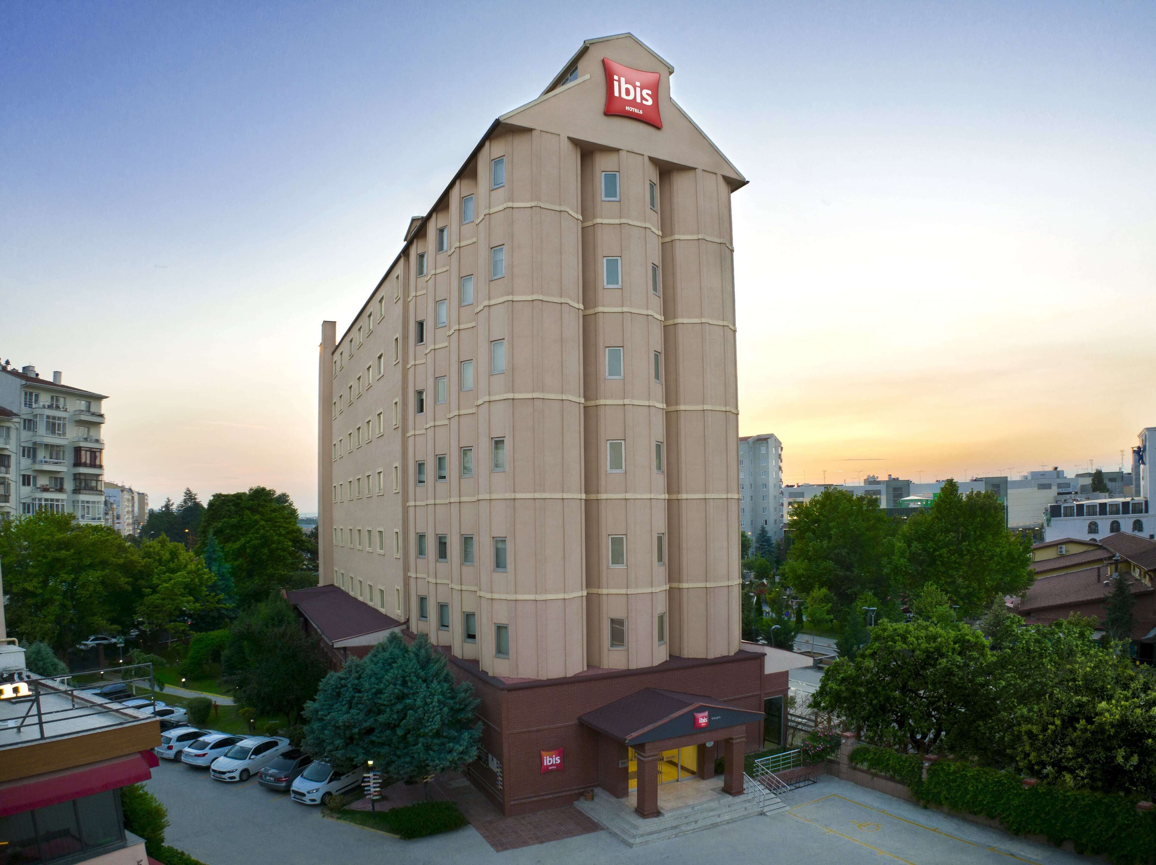 A tall, beige hotel with a prominent 'ibis' sign at the top.