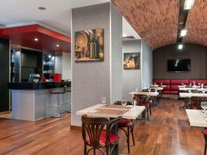 A restaurant with wooden flooring, red accents, and a bar area.
