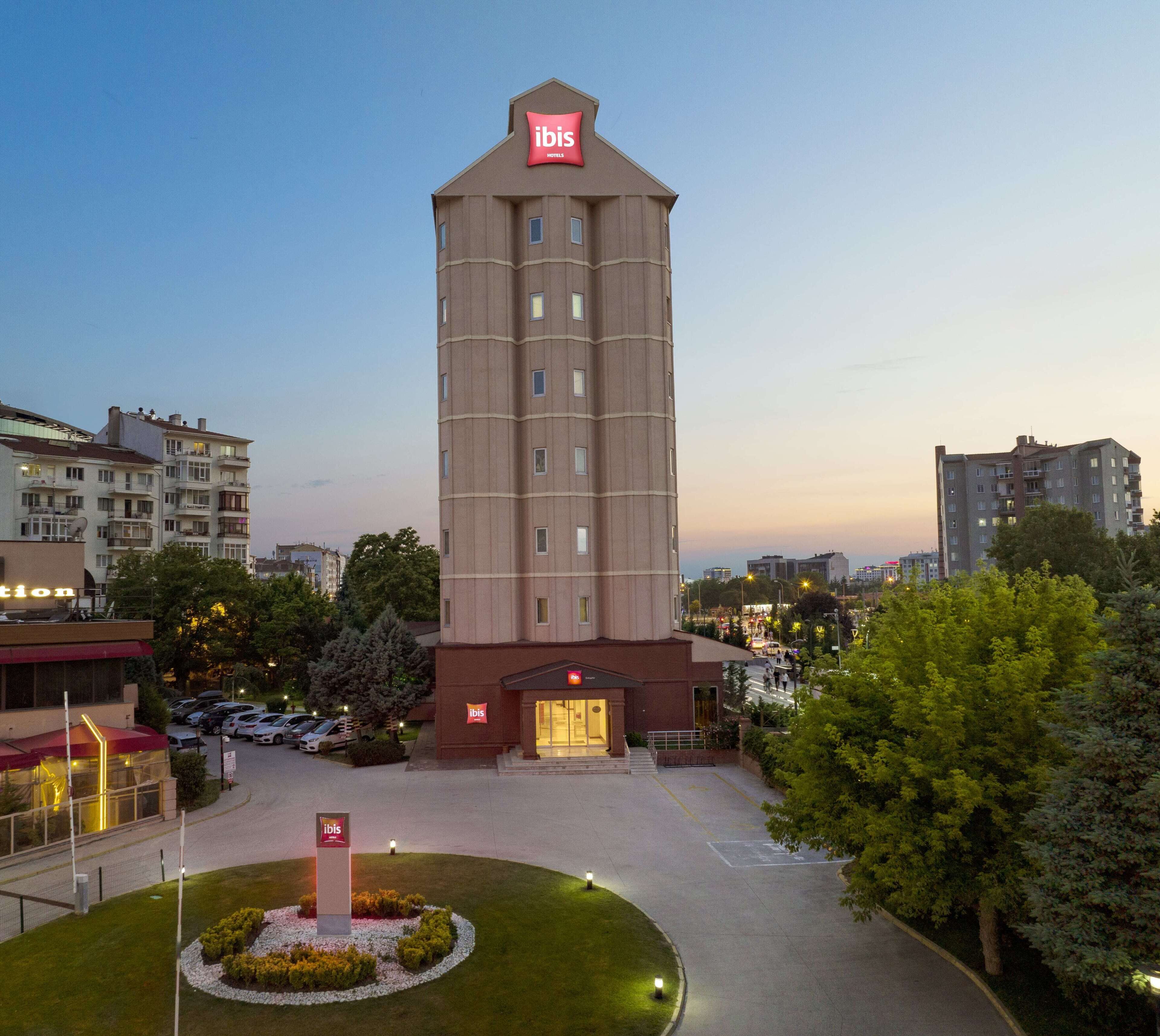 Un hotel moderno y alto, con un letrero grande de 'ibis' en la parte superior.