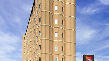 Un grand hôtel de couleur beige, sur lequel on peut voir une enseigne « ibis » bien visible au sommet et à l’entrée.
