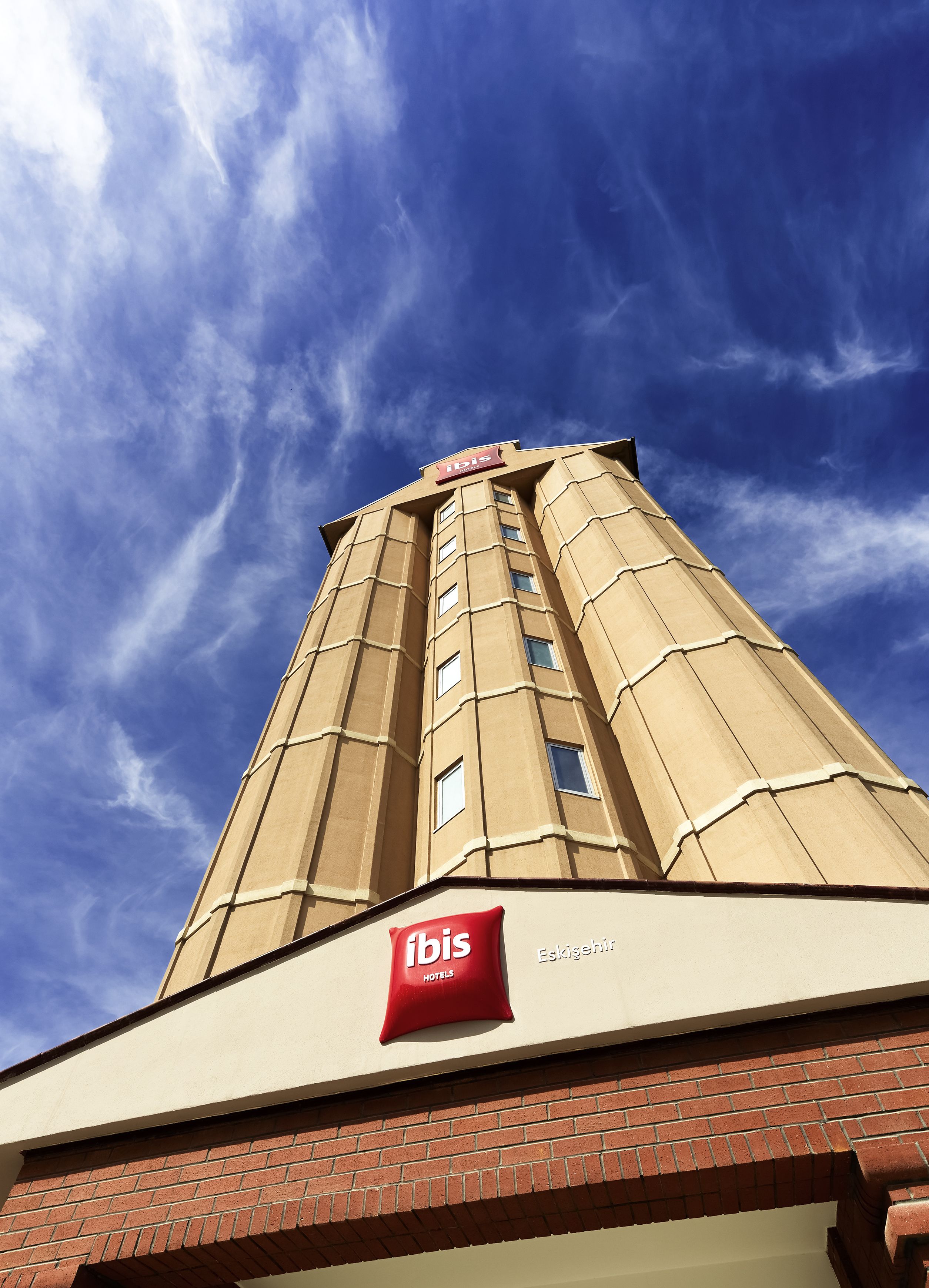 A tall hotel building with a prominent 'ibis' sign on the facade.