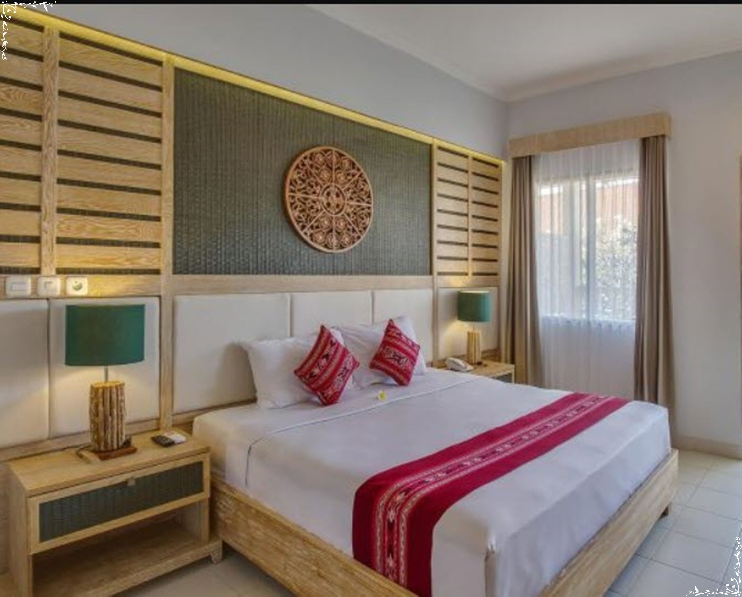 A hotel room with a large bed, wooden headboard, two bedside tables with lamps, a decorative wall piece, and a window with curtains.