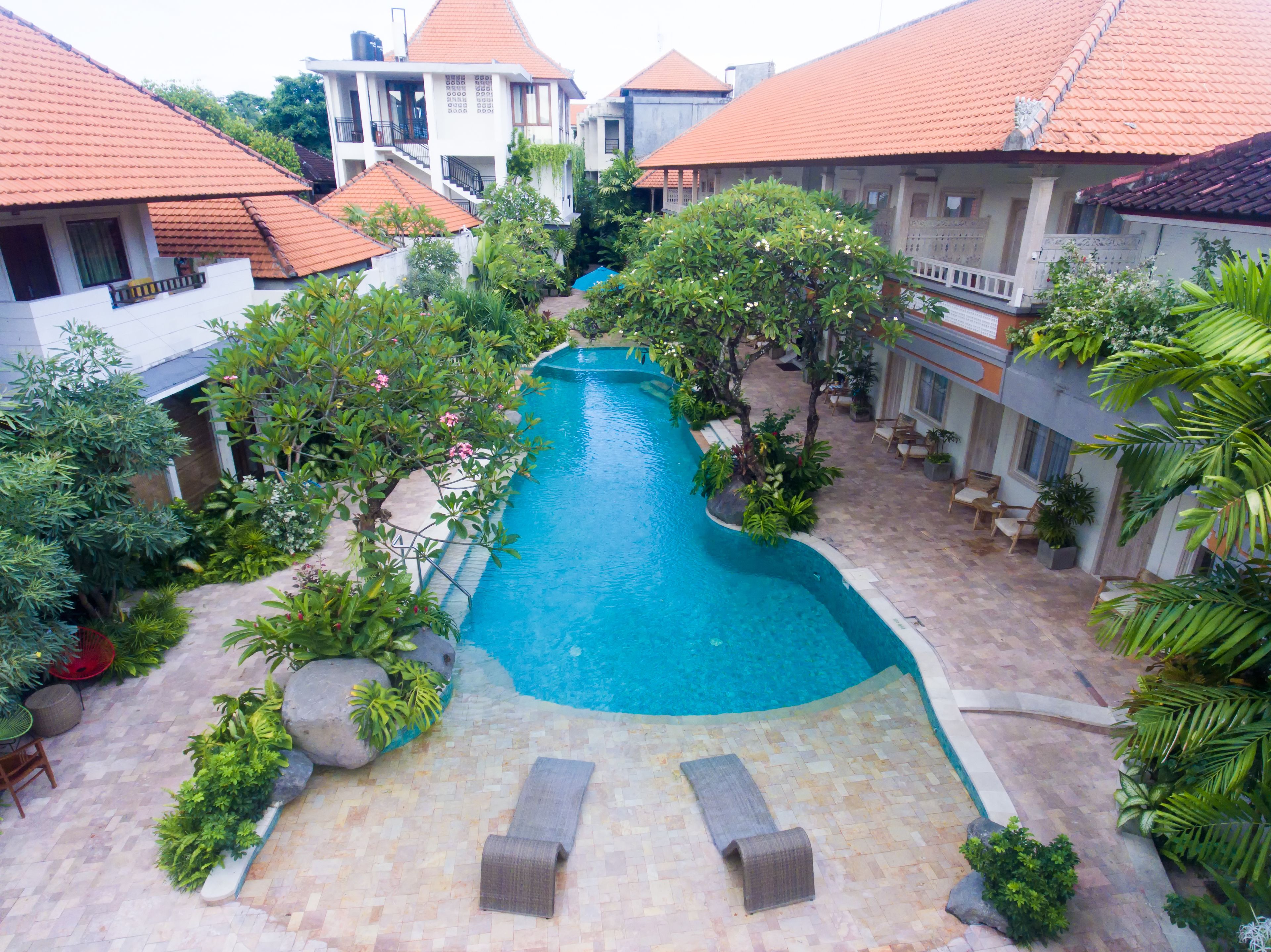Une piscine dotée d’une terrasse carrelée, entourée d’une végétation luxuriante et agrémentée de quelques chaises longues.