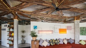 Un interior moderno con vigas de madera a la vista, un sofá rojo y varios objetos decorativos.