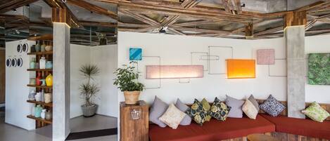 A modern interior with exposed wooden beams, a red sofa, and a variety of decorative items.