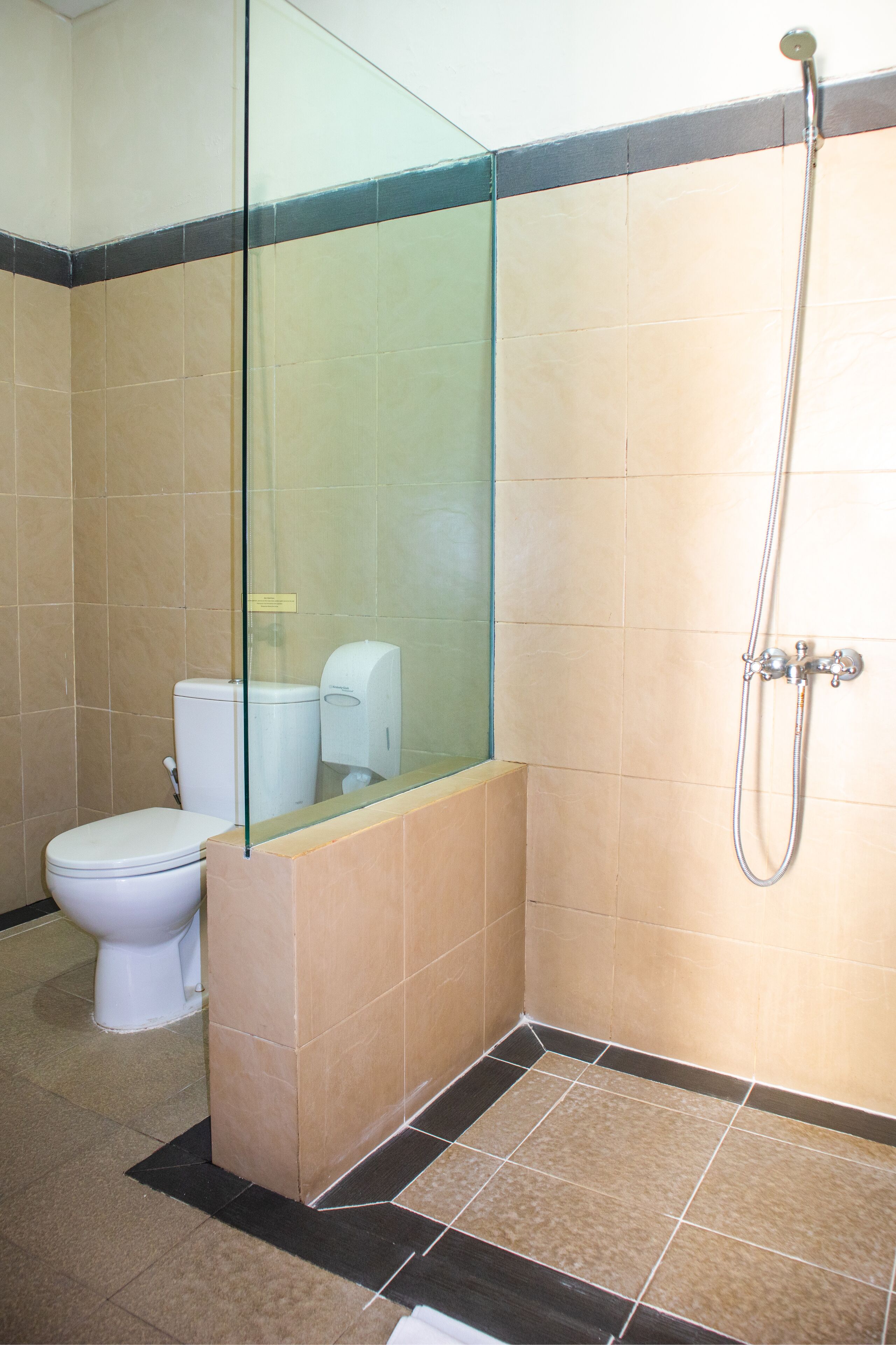 Un baño con cabina de ducha de vidrio, inodoro y secador de manos.