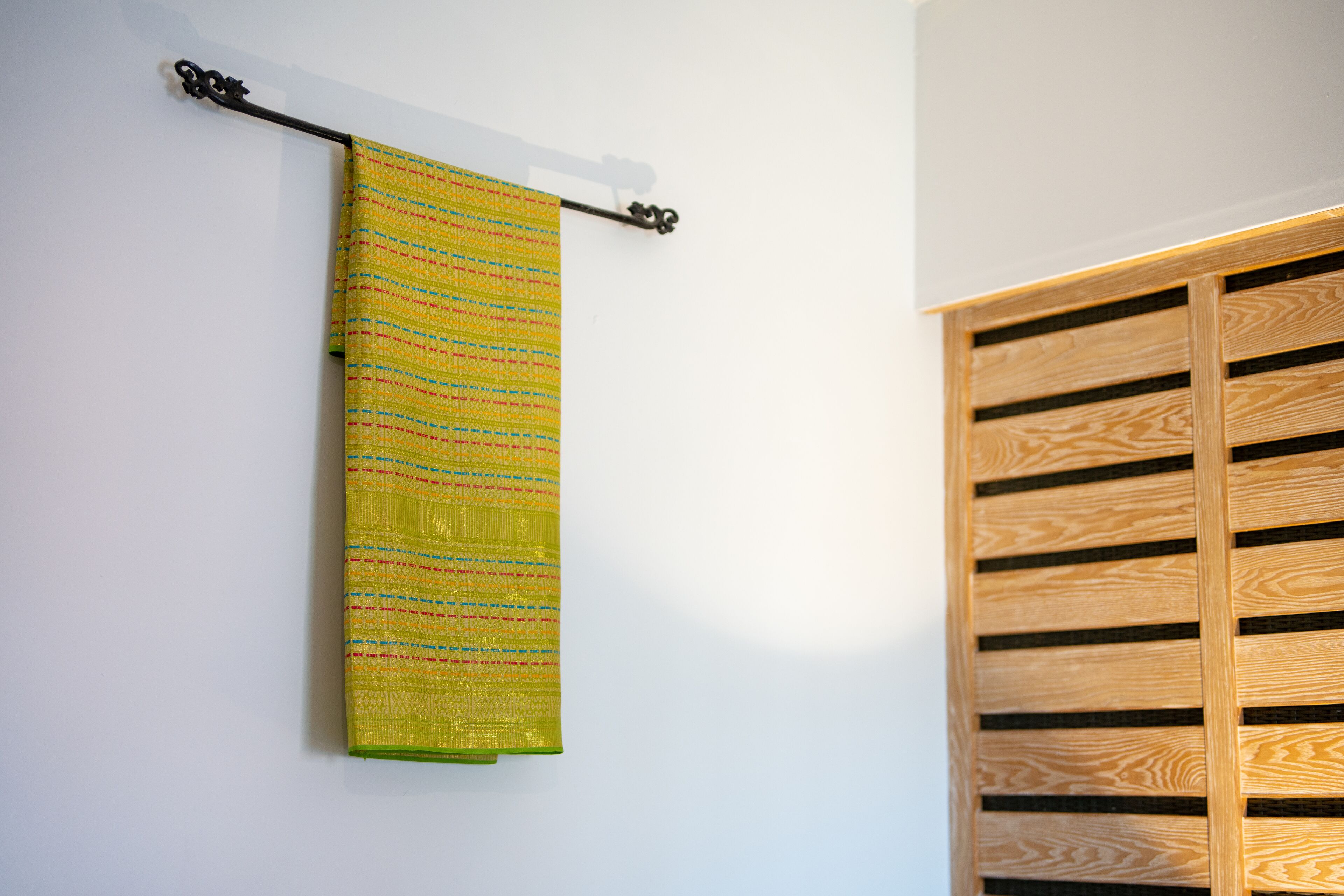 Una habitación con un armario de madera y una toalla estampada colgada.